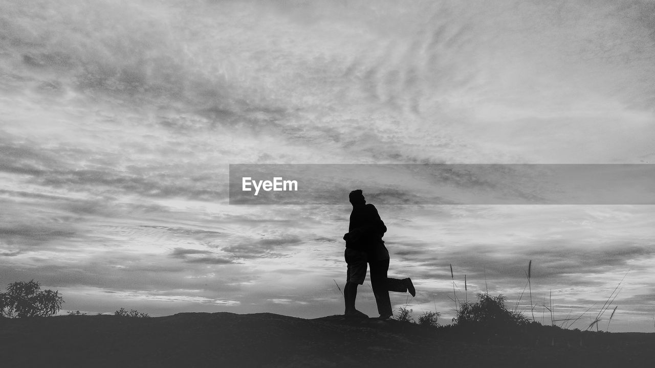 REAR VIEW OF SILHOUETTE MEN STANDING ON LAND