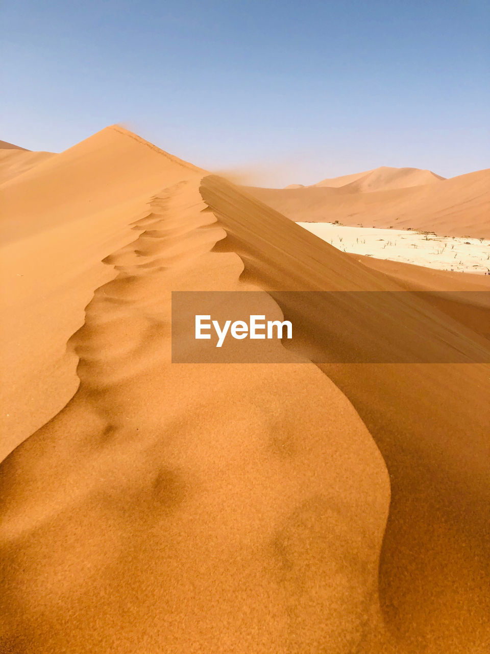 Sand dunes in desert against clear sky