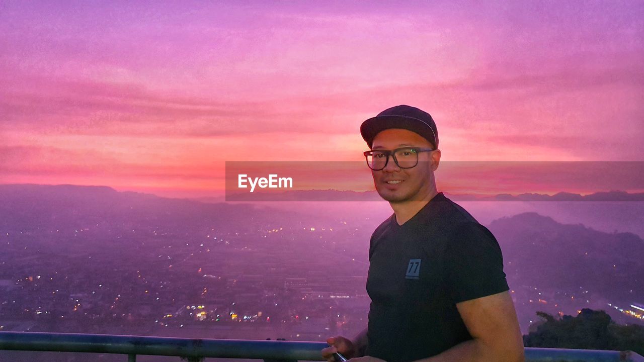 PORTRAIT OF YOUNG MAN AGAINST PURPLE MOUNTAINS AGAINST SKY