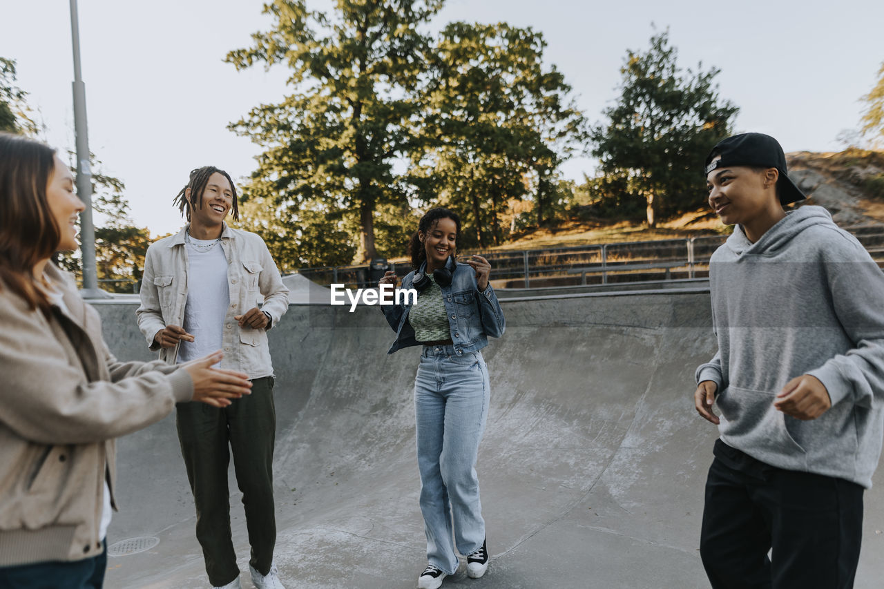 Teenagers standing in skate park, talking and laughing