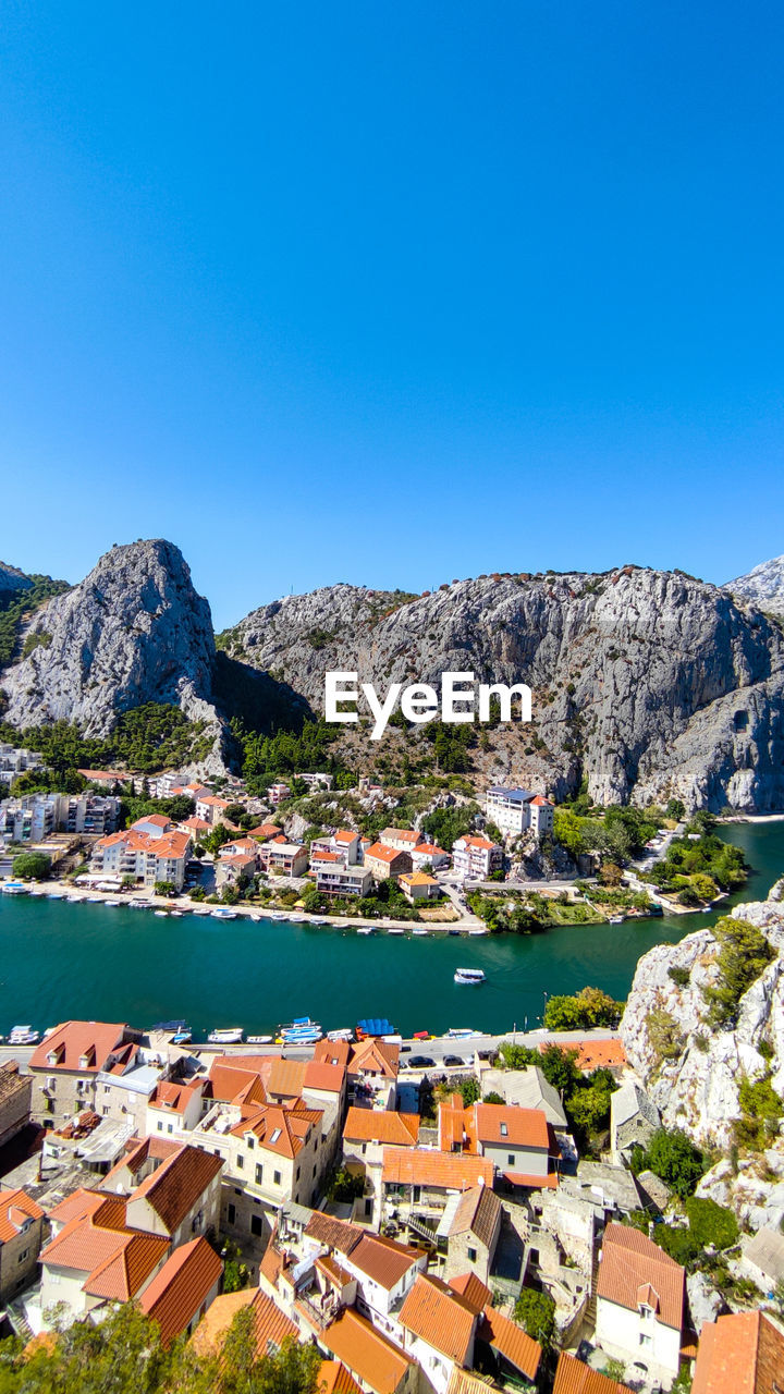 Buildings by sea against clear blue sky