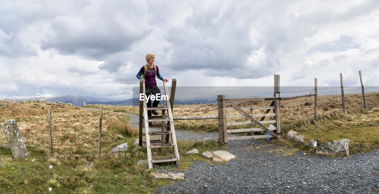 Senior woman standing on ladder by fence at cadair idris