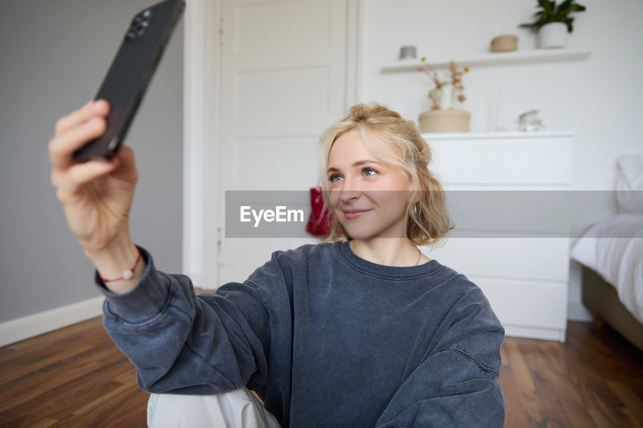 portrait of young woman using mobile phone while sitting at home