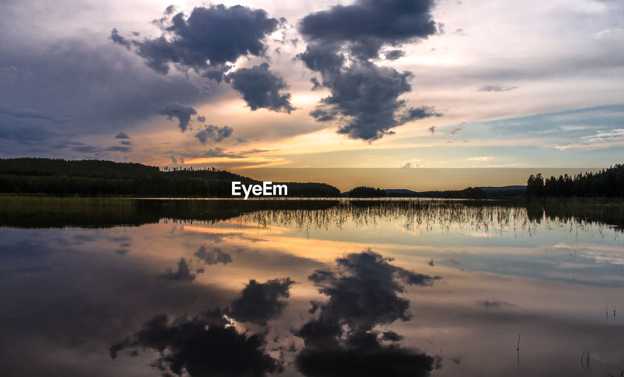 Scenic view of calm lake against cloudy sky