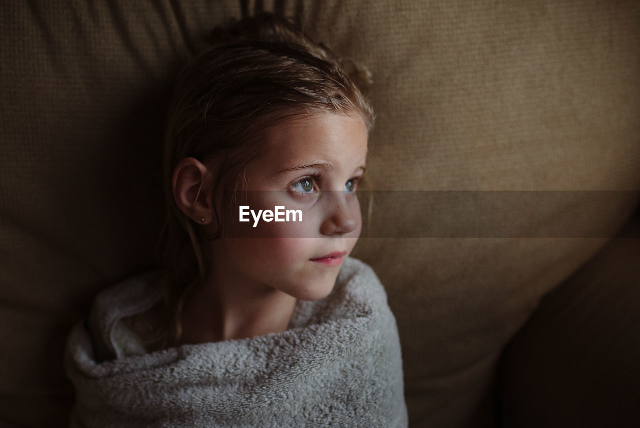 Little girl wrapped in towel after a bath looking away