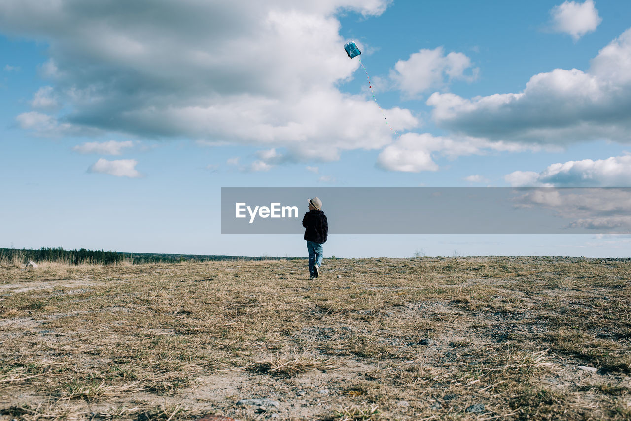 Young boy flying a kite on a hill on a beautiful sunny day