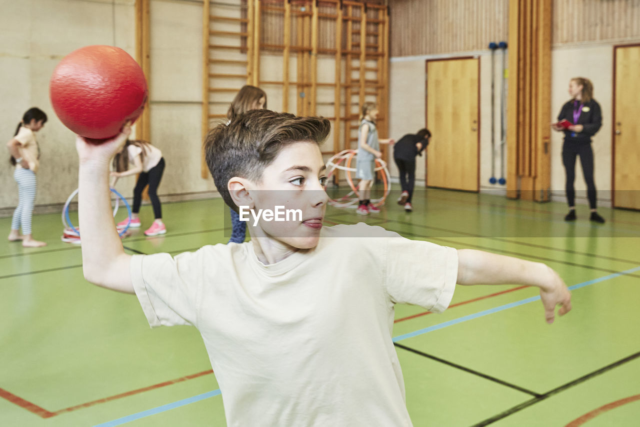 Boy throwing ball during pe class in school gym