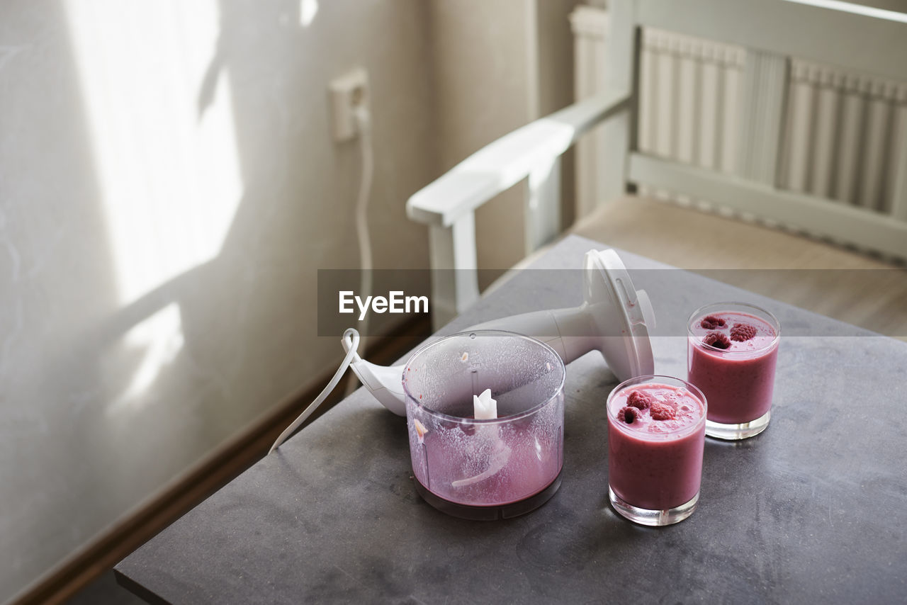 Blender and smoothie in glasses on kitchen table
