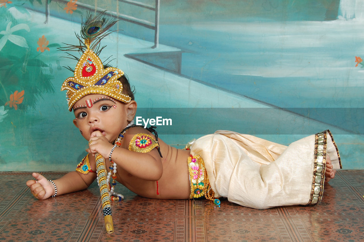 Portrait of cute boy wearing costume lying down on floor