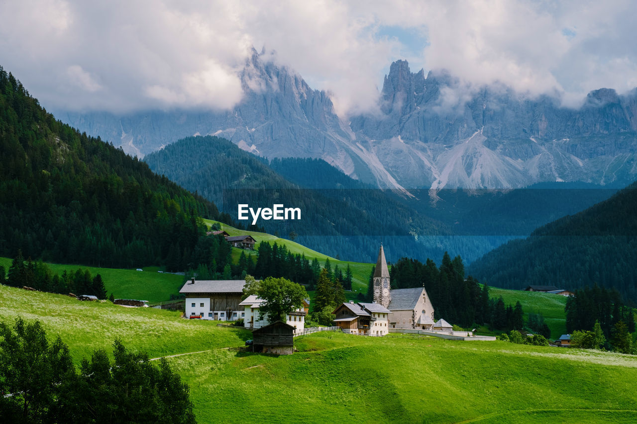 Houses on field by mountains against sky