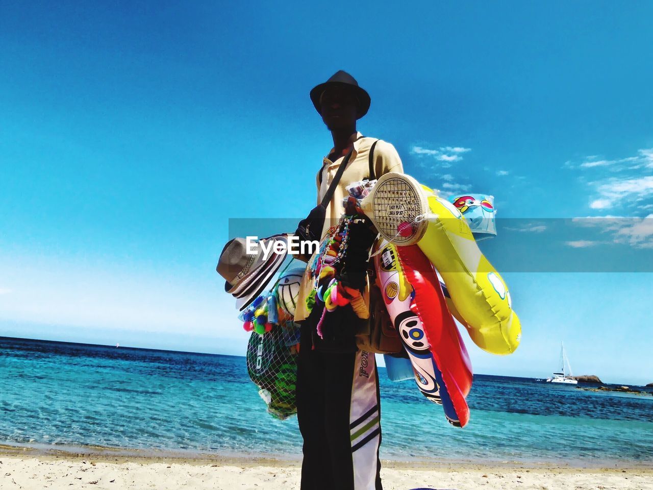 MAN HOLDING UMBRELLA AGAINST BLUE SEA