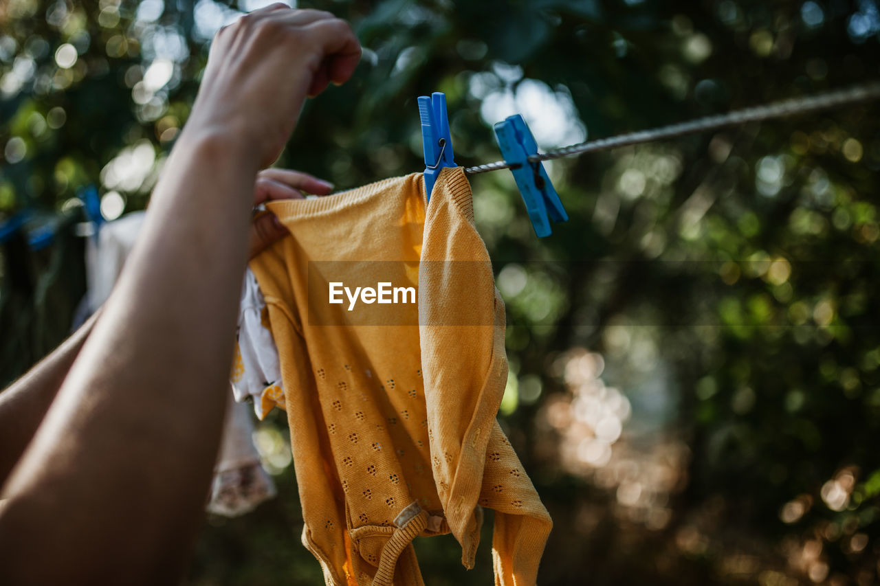 Cropped hand of woman drying clothes on clothesline