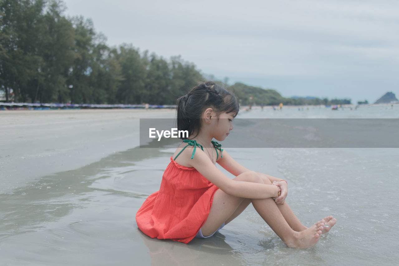 Cute girl looking down with sitting at beach