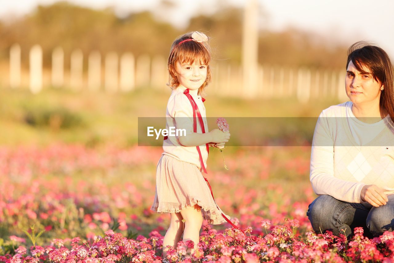 Portrait of woman with daughter amidst flowering plants