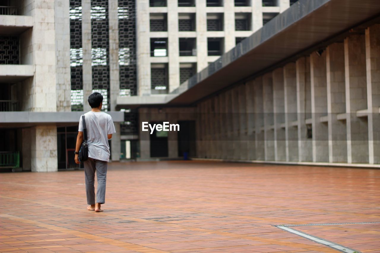 REAR VIEW OF MAN WALKING IN BUILDING