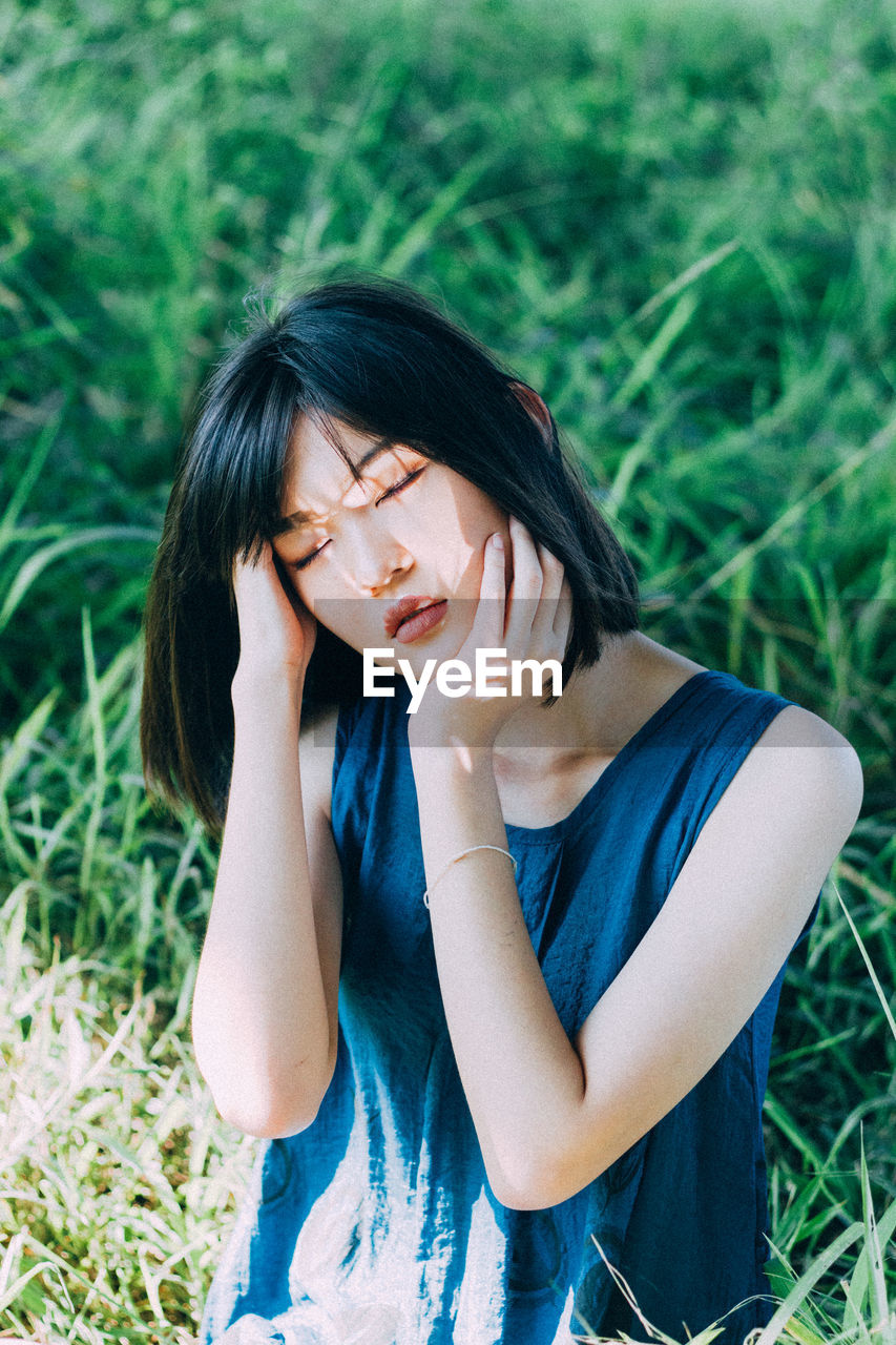 Young woman with eyes closed standing amidst plants