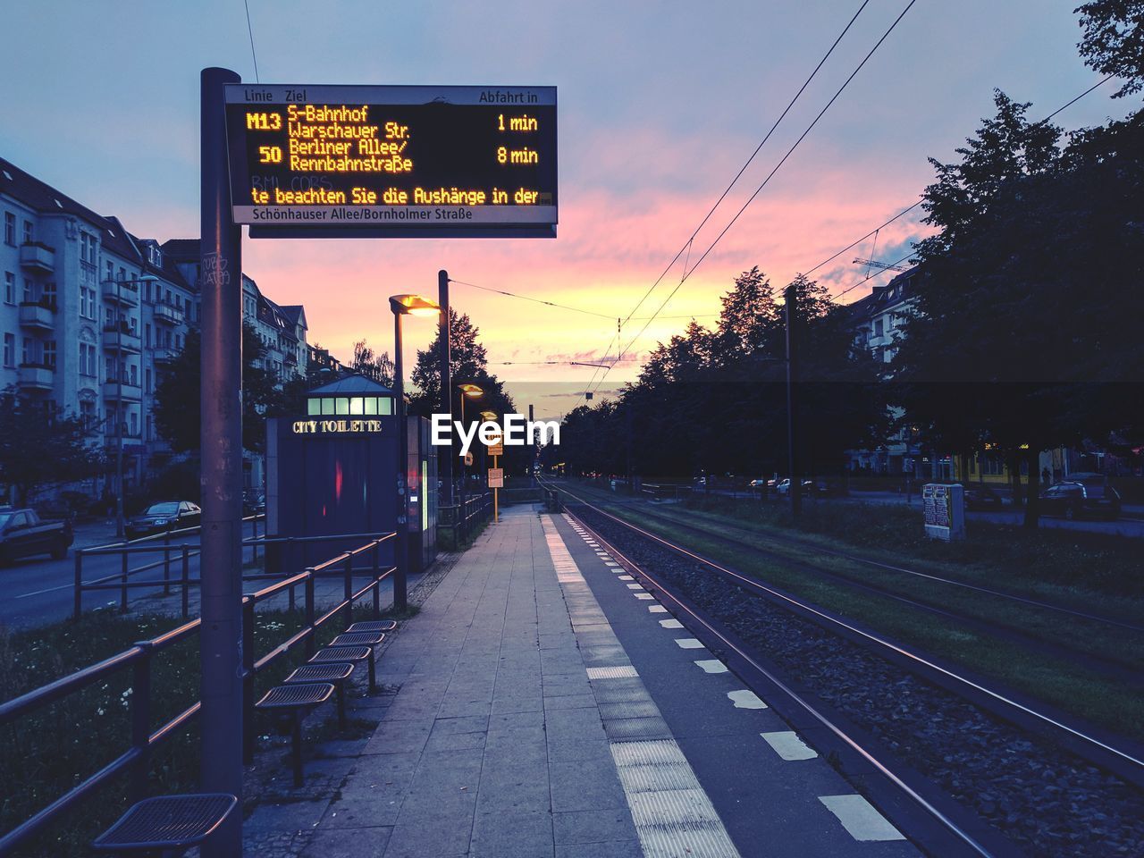 Railroad station platform against sky at sunset