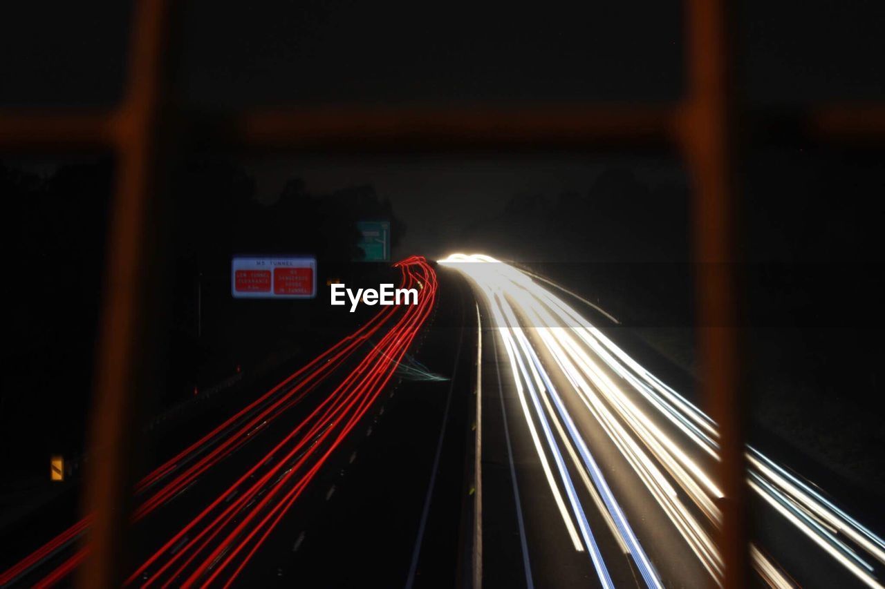 ILLUMINATED LIGHT TRAILS ON ROAD AT NIGHT