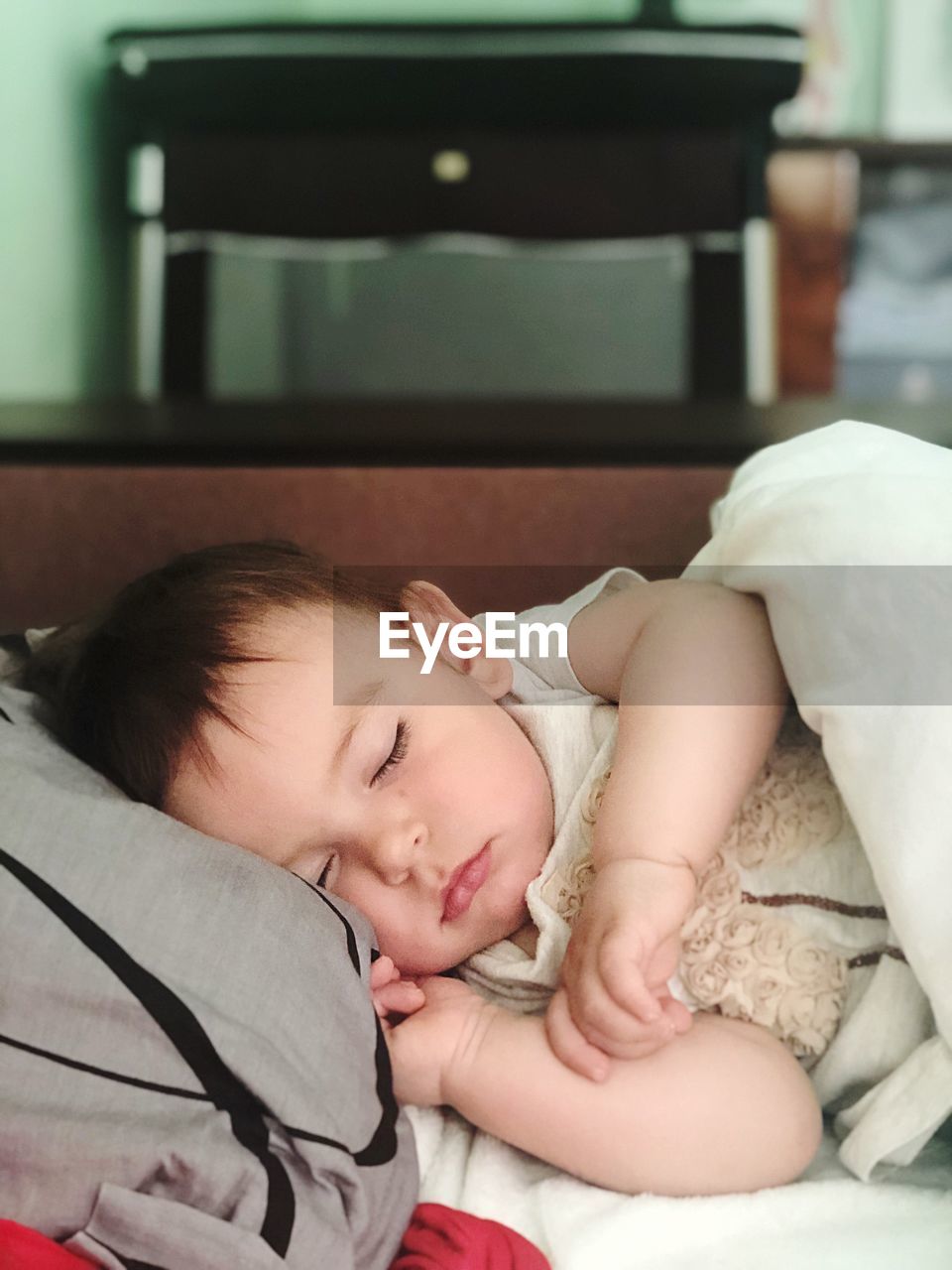 Cute baby girl sleeping on bed at home