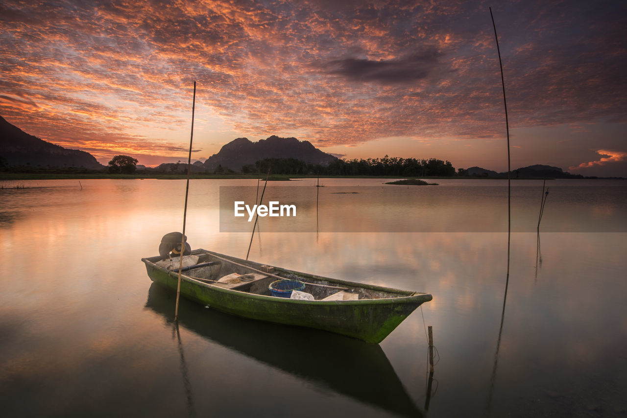 Boat moored in lake against sky during sunset