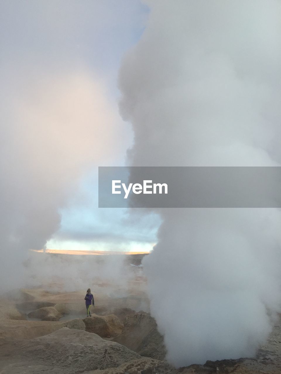 Woman walking by erupting volcano