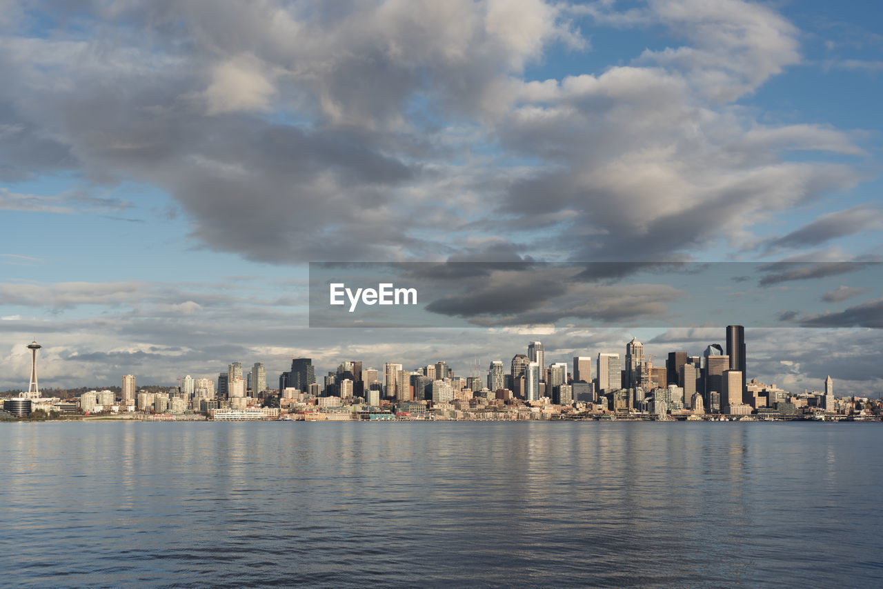 Sea by buildings in city against sky