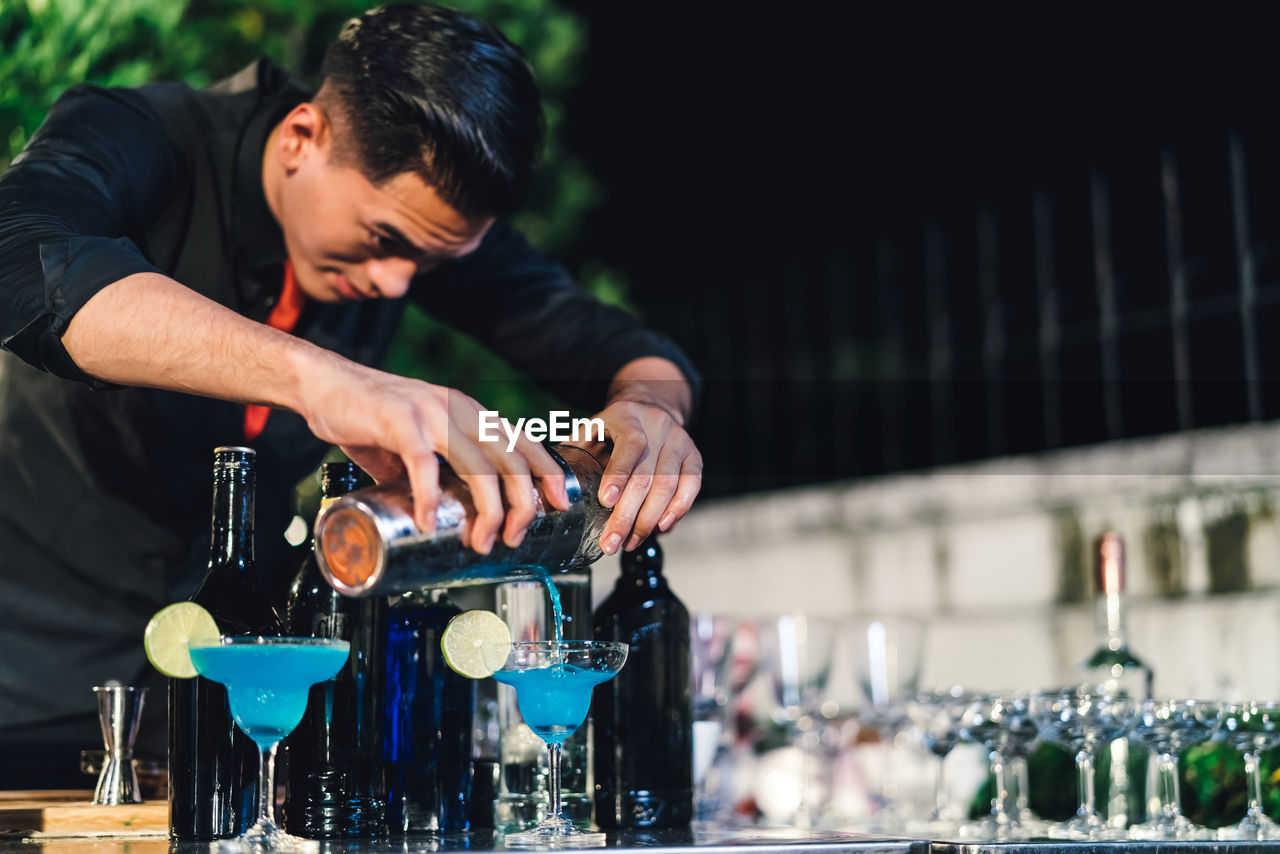 Young bartender working in party at night