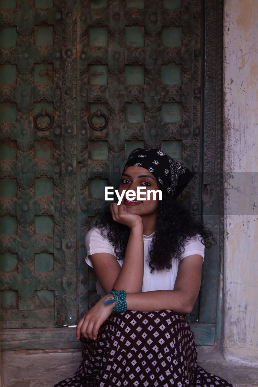 Portrait of woman sitting against wall