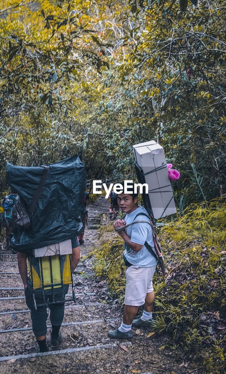 People carrying package on back against trees