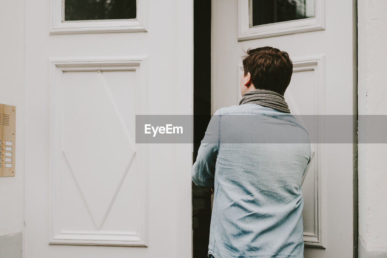 Rear view of young man entering house