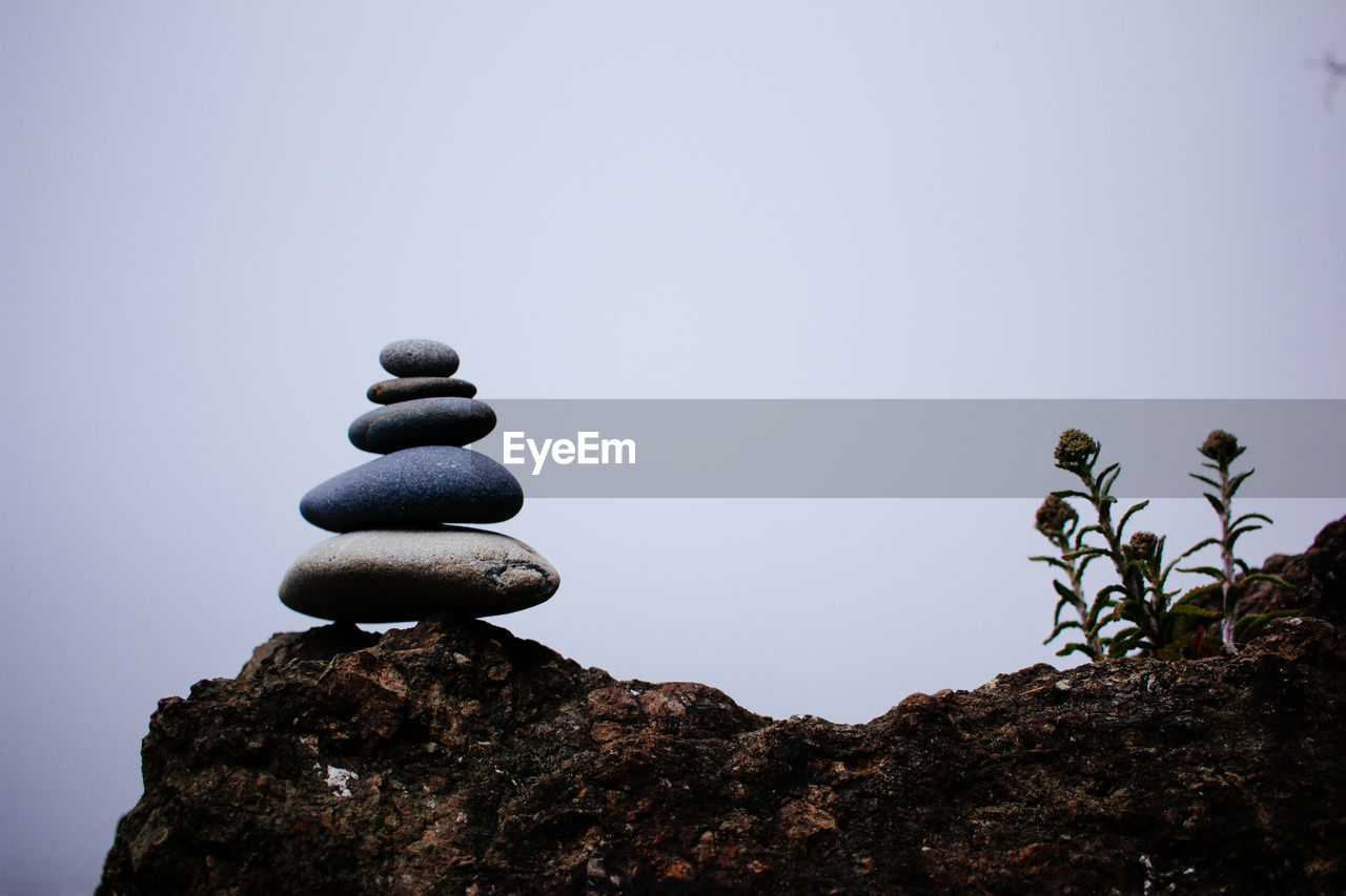 Stack of stones on rock against clear sky