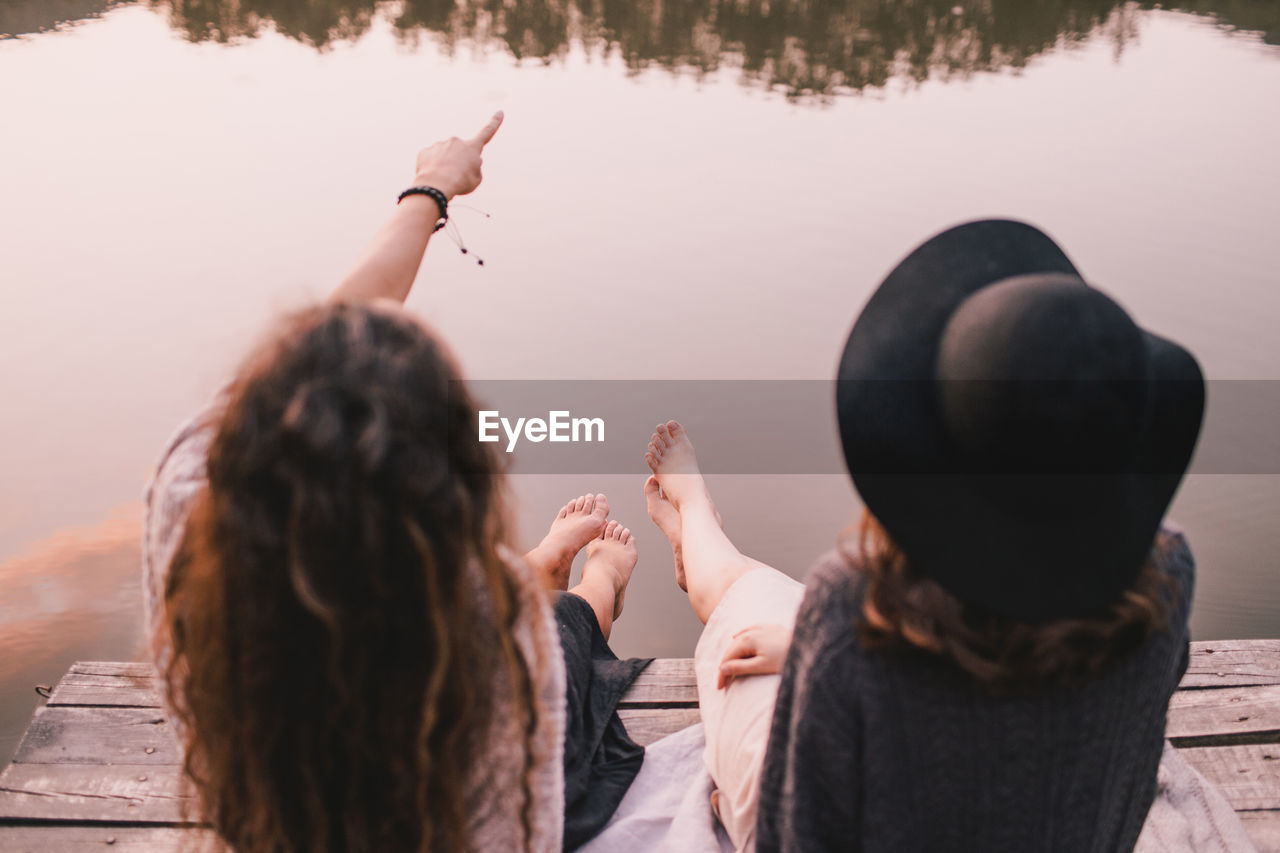 Rear view of female friends sitting on pier