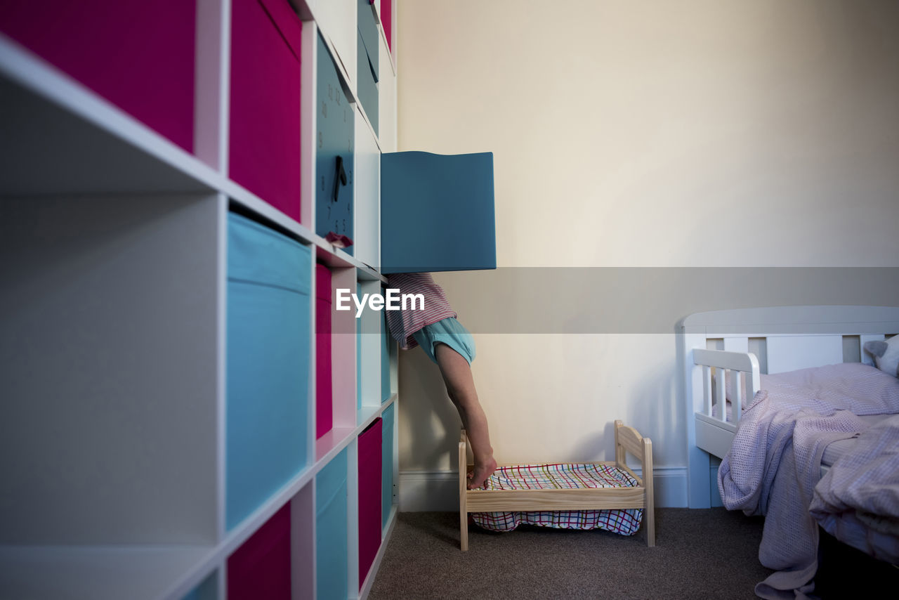 Low section of girl checking cabinet at home