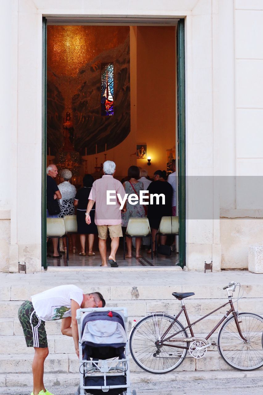 PEOPLE STANDING BY BICYCLE PARKED IN CITY