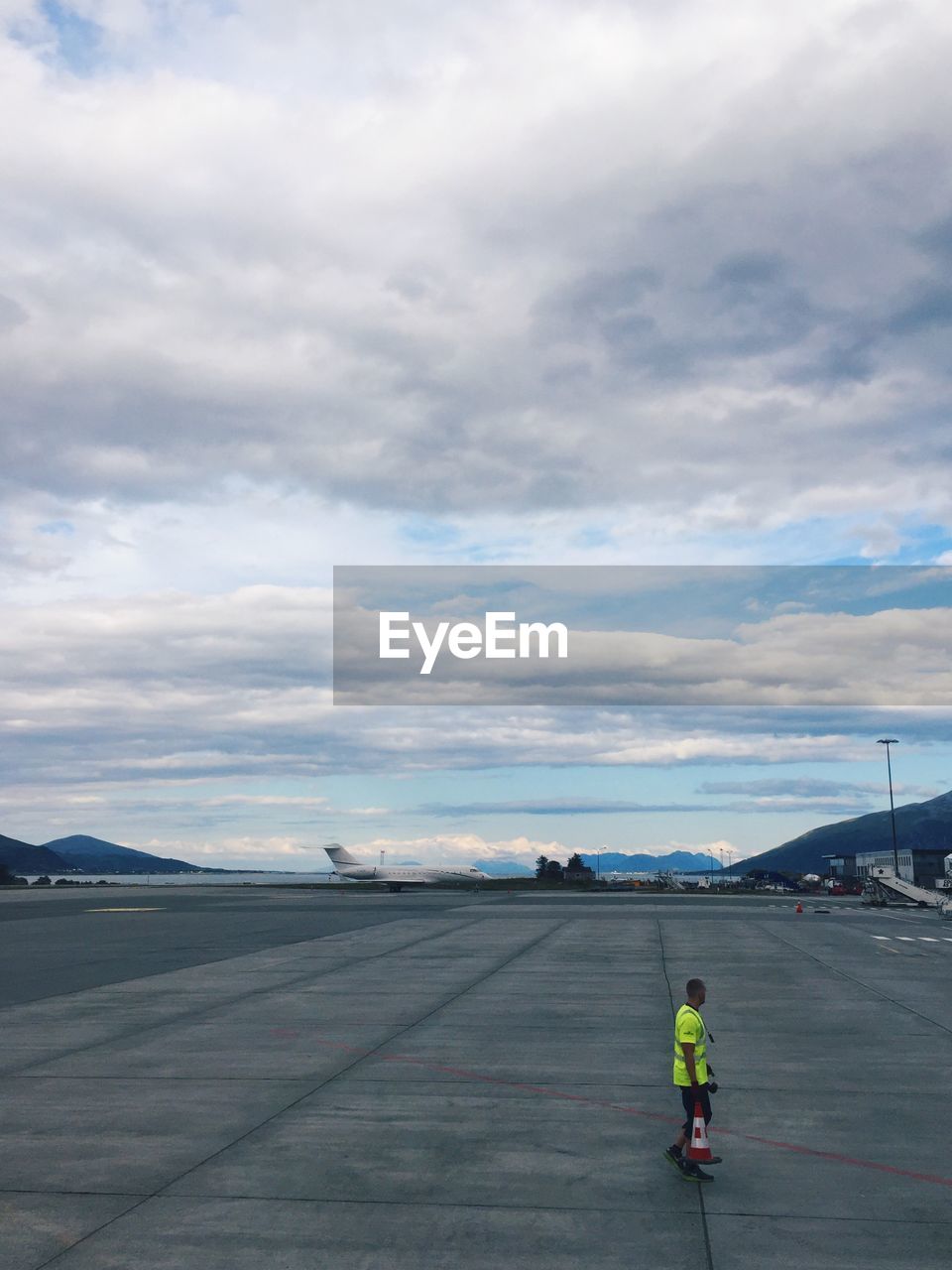 REAR VIEW OF MAN STANDING ON AIRPLANE AT AIRPORT