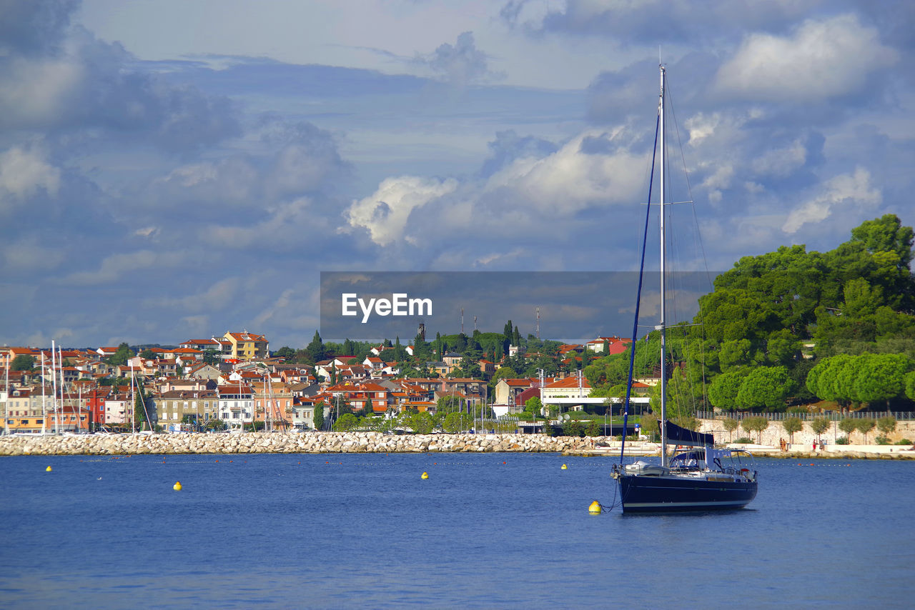 SAILBOATS ON SEA BY BUILDINGS AGAINST SKY