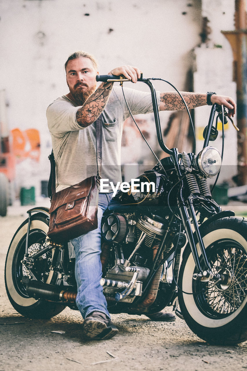 Full length portrait of man sitting on motorcycle on road