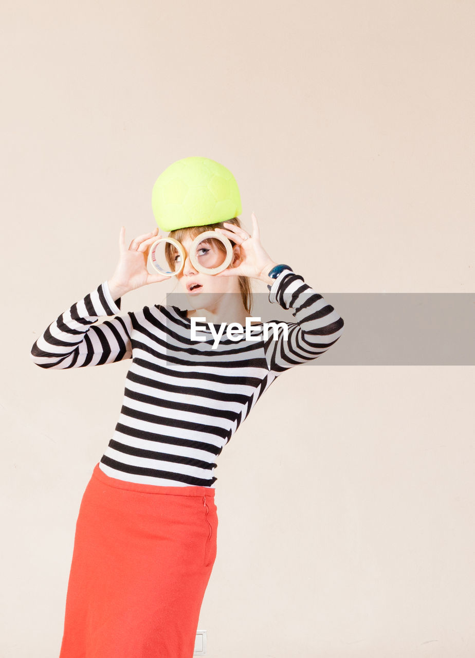 Portrait of woman holding adhesive tapes against beige background