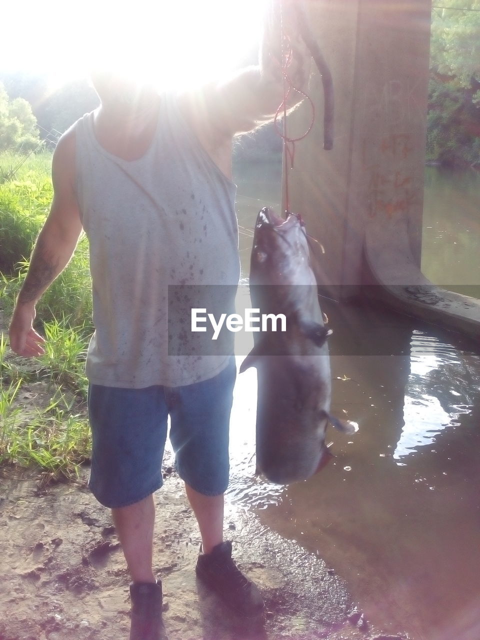 Full length of man holding fish at riverbank