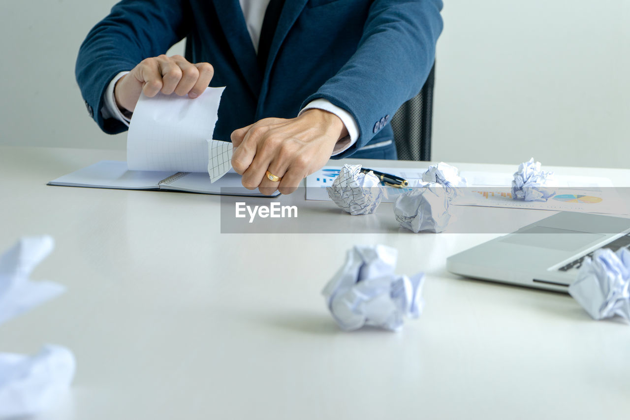 REAR VIEW OF MAN WORKING ON TABLE AT HOME