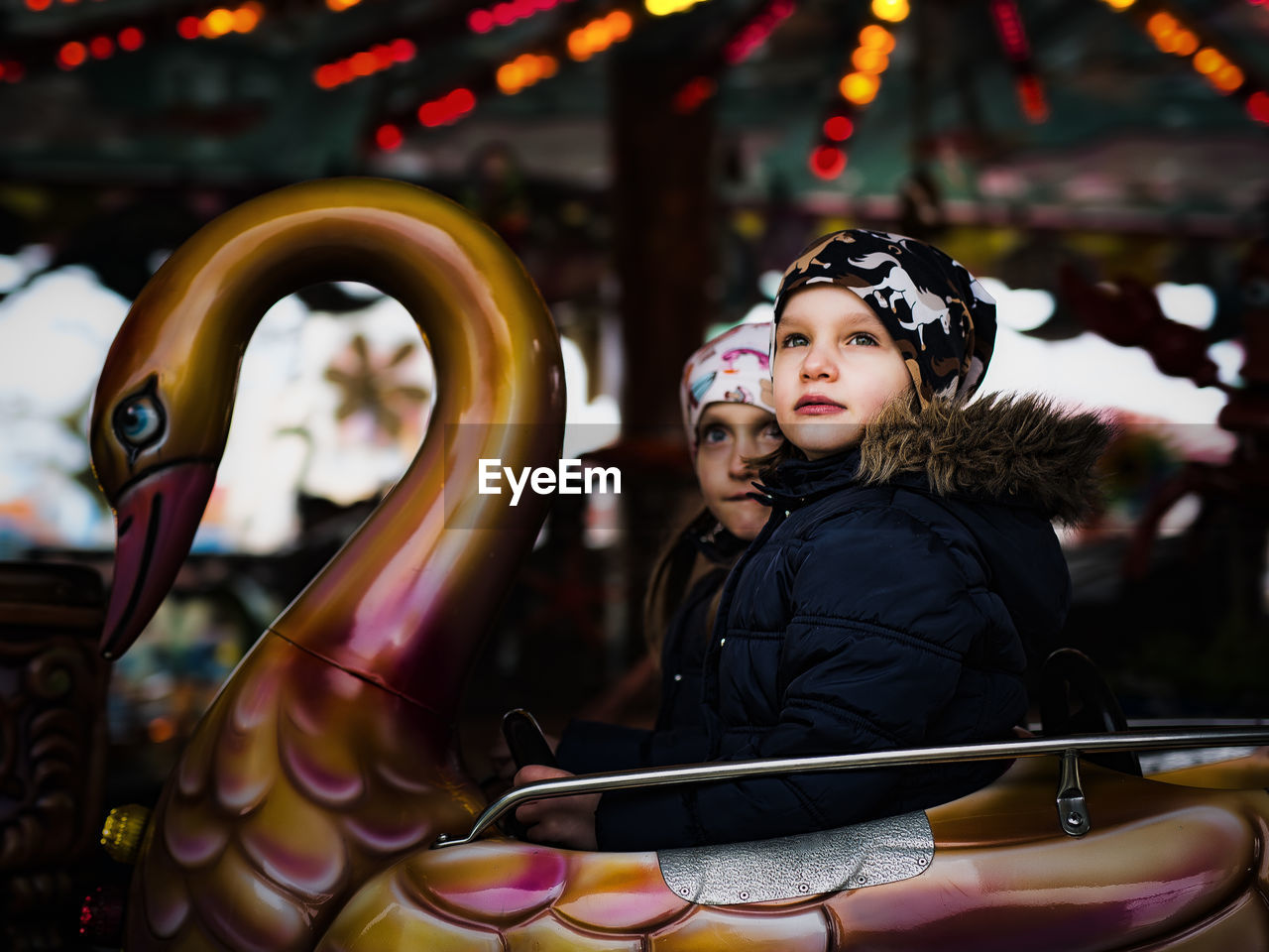 Girls looking away while sitting on amusement park ride