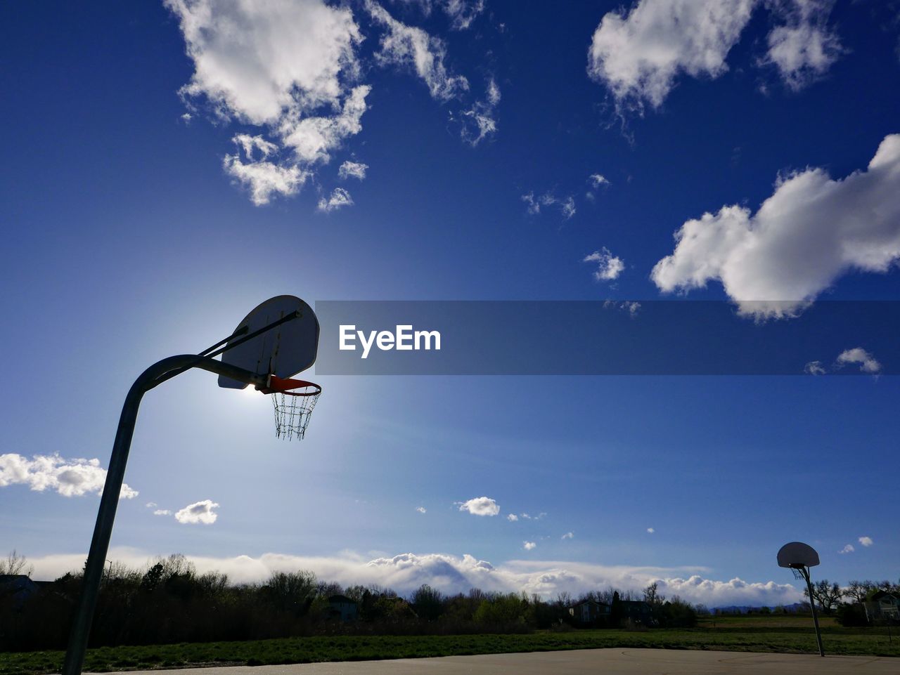 LOW ANGLE VIEW OF BASKETBALL HOOP IN FIELD AGAINST SKY