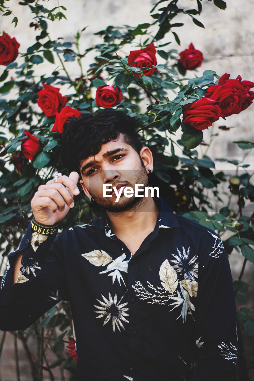 Portrait of young man standing against plants