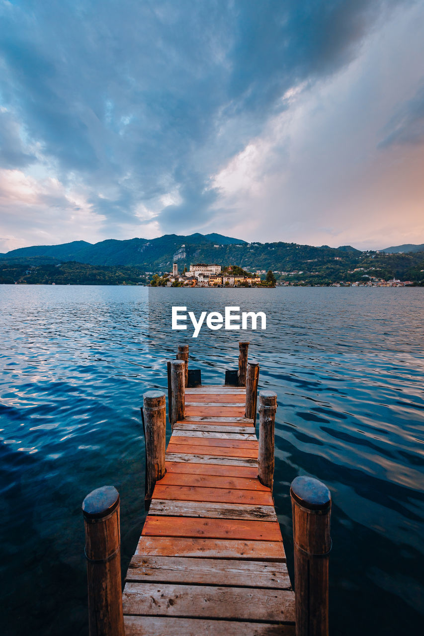 The island of san giulio with a wooden jetty in the foreground at sunset