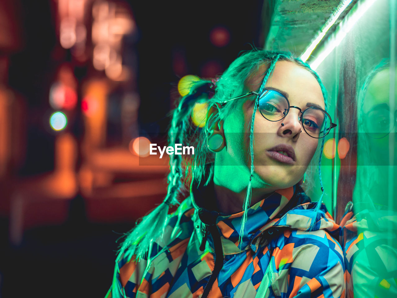 Close-up portrait of young woman standing outdoors at night