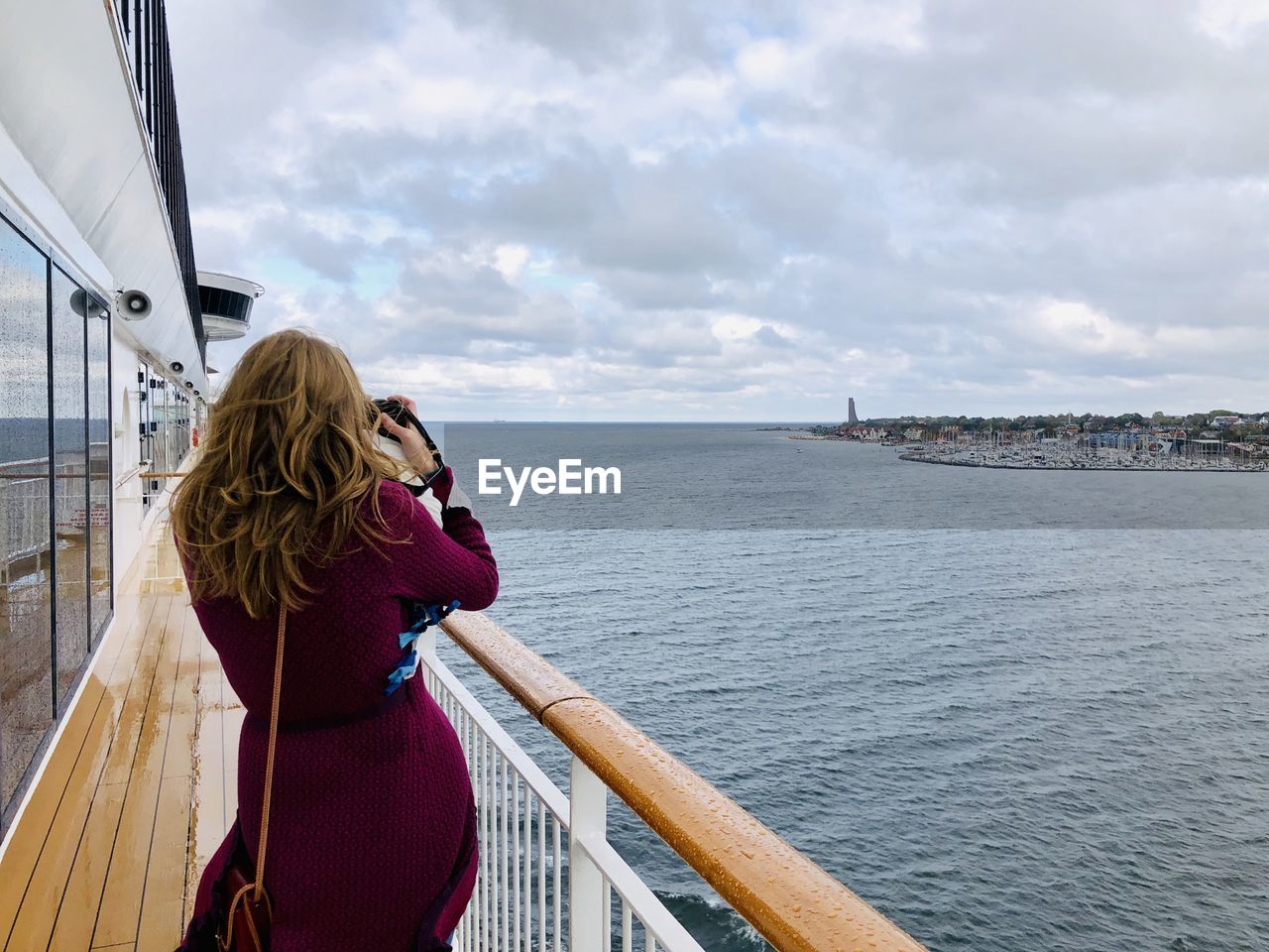 Rear view of woman photographing by sea against sky