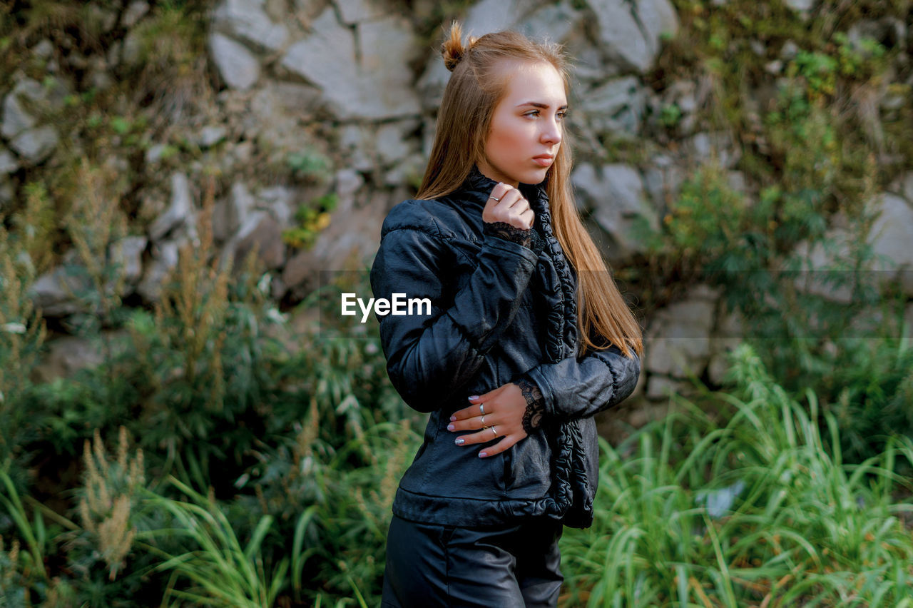 Young woman wearing black warm clothing against rock formation