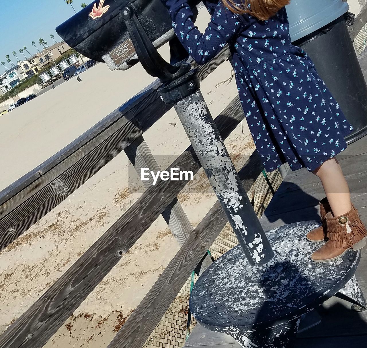 Low section of girl standing by fence at beach