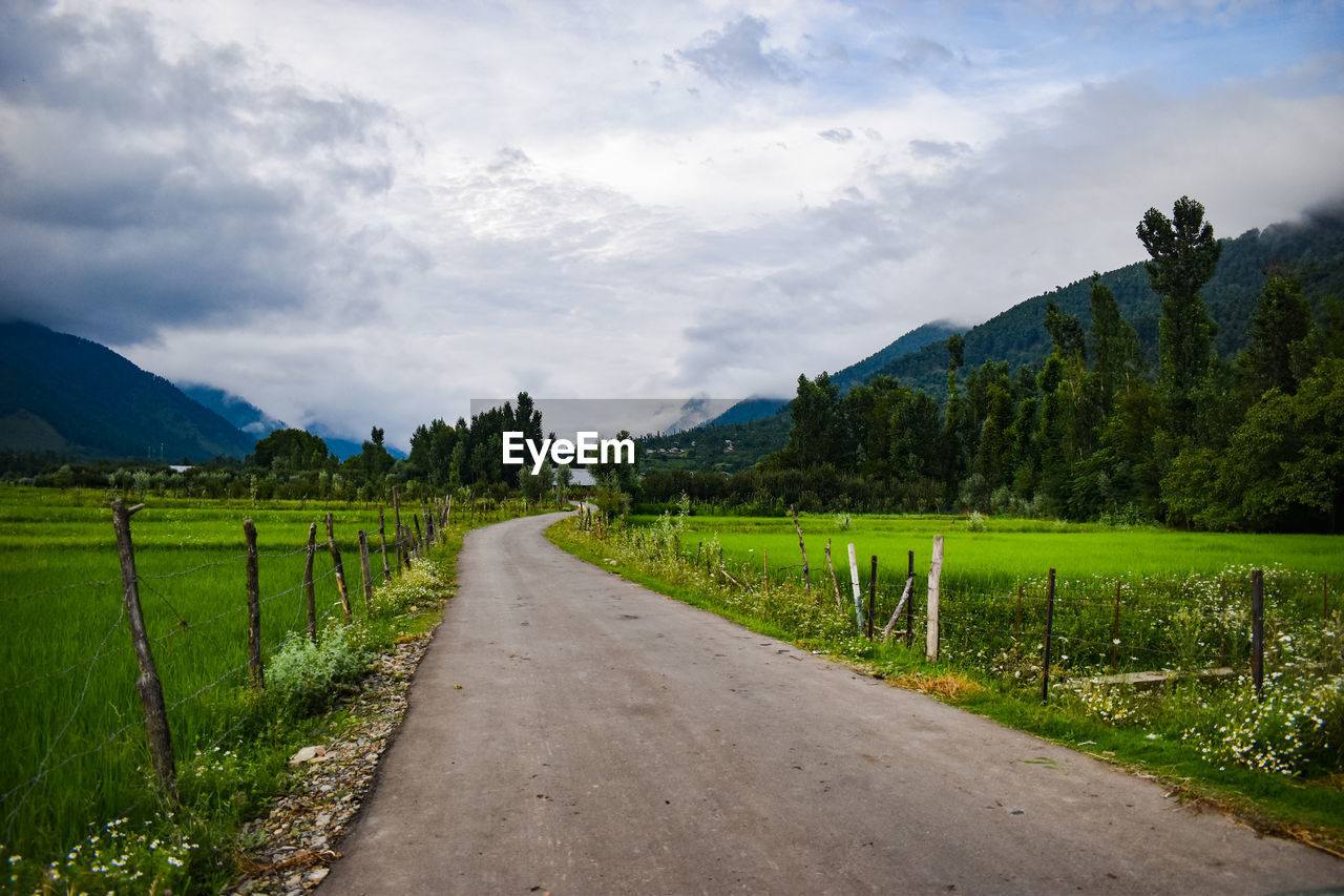 Road amidst field against sky