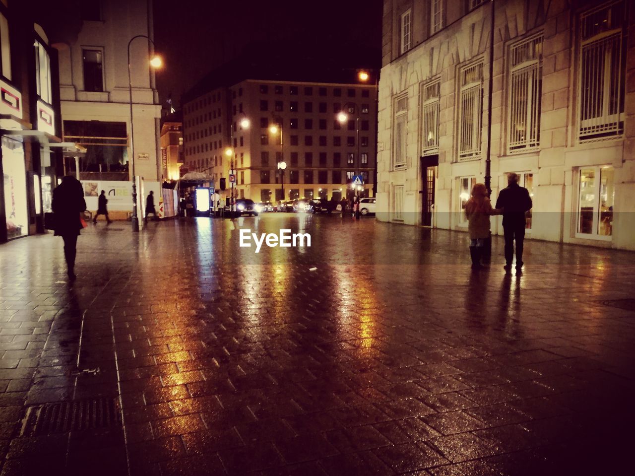 PEOPLE WALKING ON ILLUMINATED STREET AT NIGHT